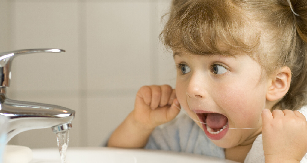 children begin flossing - little girl flossing